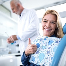A woman giving a thumbs-up at a dental office.