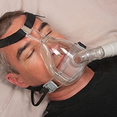 man sleeping while wearing CPAP machine 