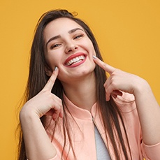 woman smiling and pointing at her smile (for benefits of Candid clear aligners section)