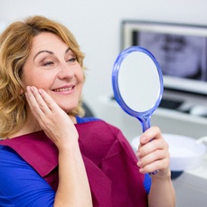 dental patient admiring her new smile in the mirror