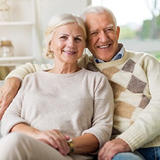 Sitting older couple enjoying benefits of dental implants in Arlington