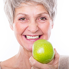 Smiling senior woman holding an apple