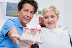 Dentist showing patient implant post model