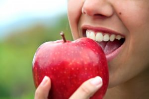 close up of person eating a red apple