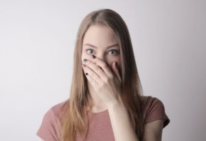 Woman with strange dental emergency covering her mouth