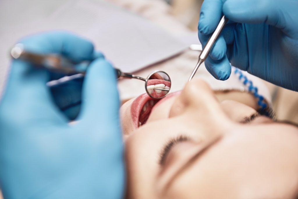 Dentist examining patient’s teeth at dental checkup