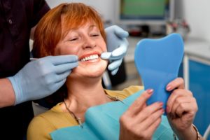 a woman smiling at the dentist with his new dental implants after having dentures