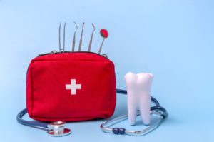 Fake tooth next to red emergency bag and dental instruments